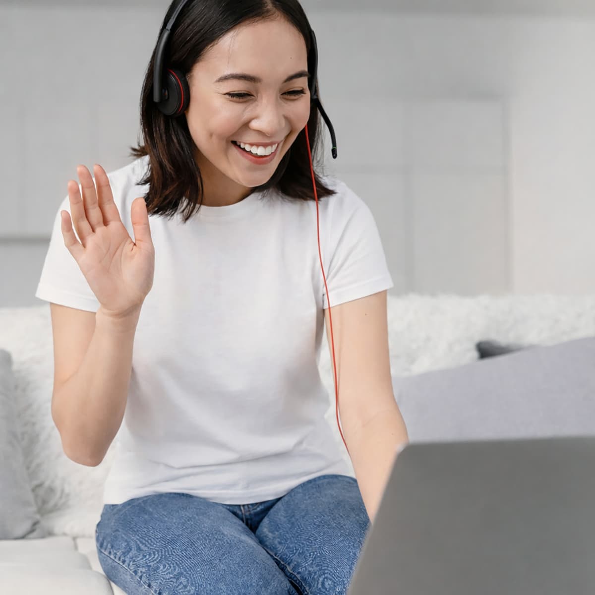 Smiling woman on headset waving during online wellness consultation over video call